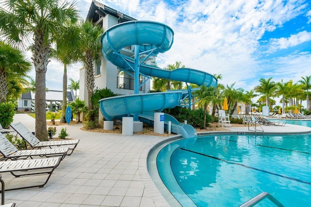 community pool featuring a water slide and a patio area