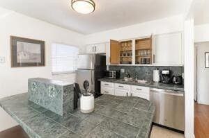 103 SE 5th Ave, Boynton Beach, FL 33435 - kitchen with dishwasher, freestanding refrigerator, white cabinetry, open shelves, and backsplash