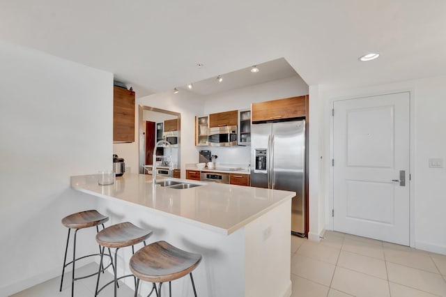 480 Hibiscus St Unit 709, West Palm Beach, FL 33401 - kitchen featuring appliances with stainless steel finishes, brown cabinets, a kitchen bar, a sink, and modern cabinets