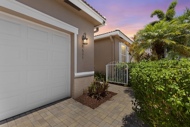 8623 Mangrove Cay, West Palm Beach, FL 33411 - exterior entry at dusk with stucco siding, a tile roof, and an attached garage