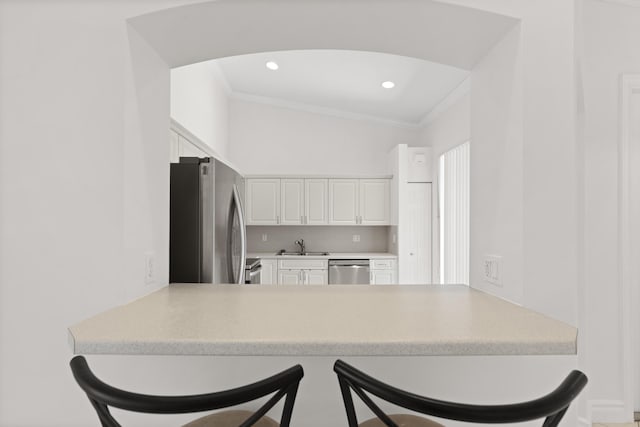 8623 Mangrove Cay, West Palm Beach, FL 33411 - kitchen with appliances with stainless steel finishes, crown molding, white cabinetry, a peninsula, and a breakfast bar
