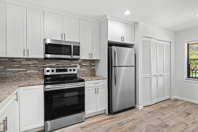 2920 SW 22nd Cir Unit C2, Delray Beach, FL 33445 - kitchen with appliances with stainless steel finishes, backsplash, light wood finished floors, white cabinetry, and baseboards