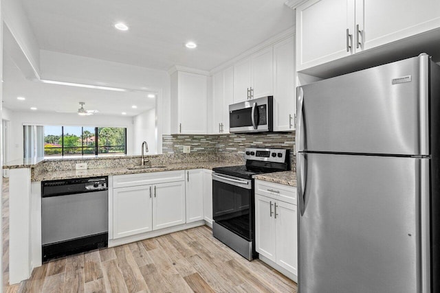 2920 SW 22nd Cir Unit C2, Delray Beach, FL 33445 - kitchen featuring stainless steel appliances, a sink, white cabinets, light wood-type flooring, and decorative backsplash