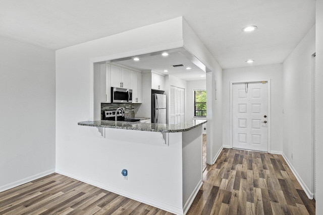 2920 SW 22nd Cir Unit C2, Delray Beach, FL 33445 - kitchen with appliances with stainless steel finishes, dark stone countertops, dark wood finished floors, white cabinets, and a breakfast bar area