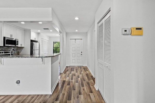 2920 SW 22nd Cir Unit C2, Delray Beach, FL 33445 - kitchen with stainless steel appliances, white cabinetry, dark stone countertops, recessed lighting, and dark wood-style floors