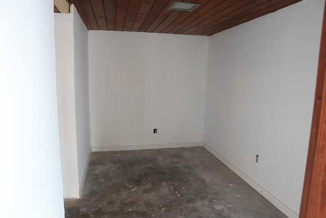 spare room with unfinished concrete flooring, wooden ceiling, and baseboards