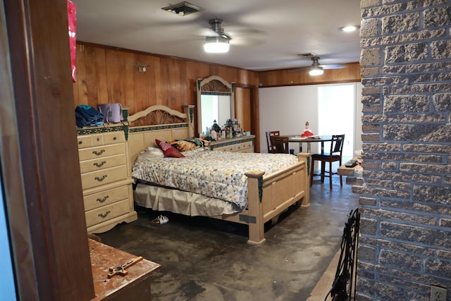 bedroom featuring finished concrete flooring and wooden walls