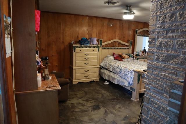 bedroom with wood walls and unfinished concrete flooring