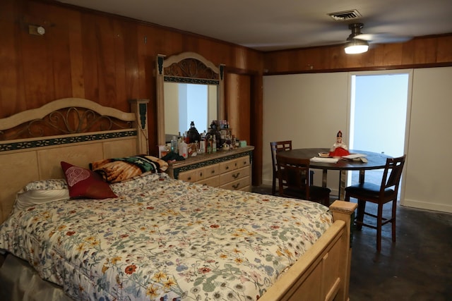 bedroom with finished concrete floors and wood walls