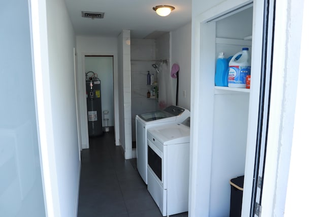 laundry area with washing machine and dryer, tile patterned flooring, and water heater