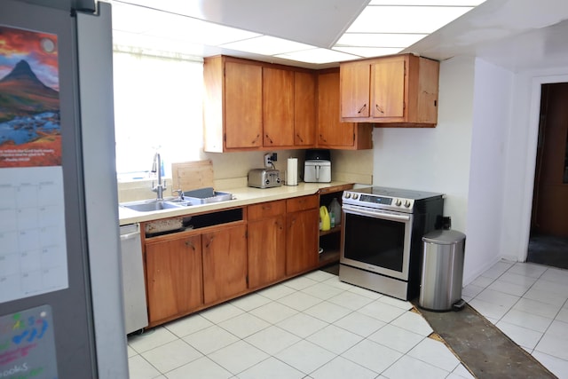 kitchen with appliances with stainless steel finishes, a sink, light countertops, and brown cabinets