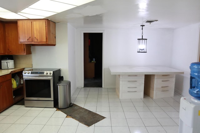 kitchen with stainless steel range with electric stovetop, light countertops, brown cabinets, decorative light fixtures, and light tile patterned floors