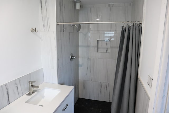 full bathroom with a tile shower and vanity