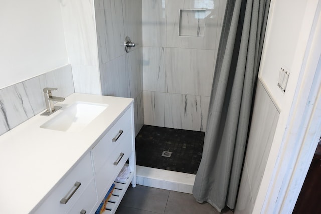 full bathroom with tiled shower, vanity, and tile patterned flooring