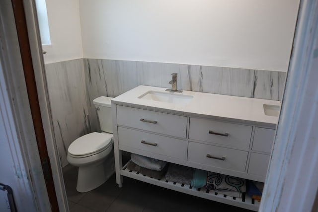 bathroom featuring toilet, vanity, wainscoting, and tile patterned flooring
