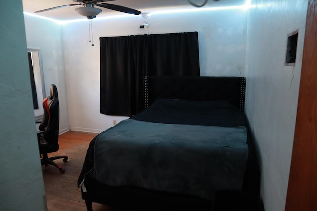 bedroom featuring wood finished floors, a ceiling fan, and baseboards
