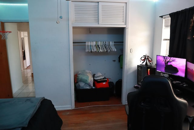 bedroom with a closet, a desk, and wood finished floors