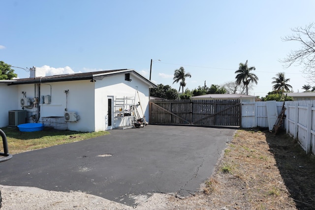 view of side of home with stucco siding, a gate, fence, cooling unit, and a cooling unit