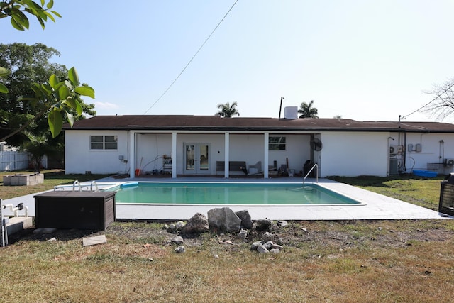 back of house featuring french doors, an outdoor pool, a lawn, stucco siding, and a patio