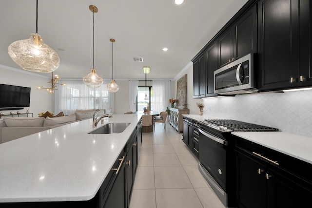 kitchen with range with gas stovetop, stainless steel microwave, open floor plan, a sink, and dark cabinets