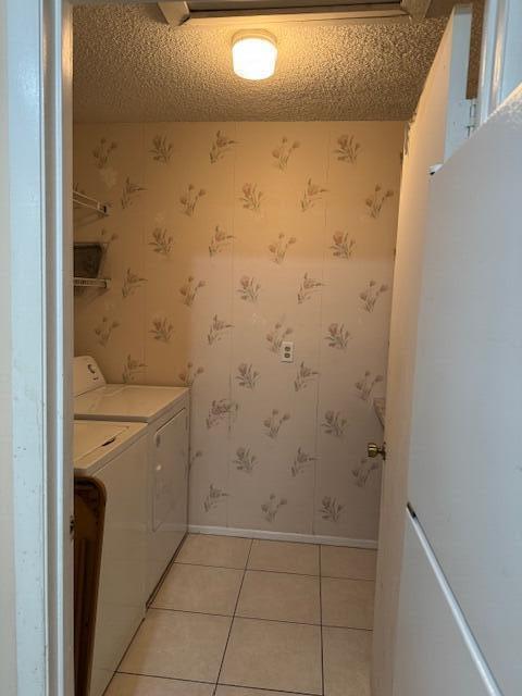 4065 NW Cinnamon Tree Cir, Jensen Beach, FL 34957 - laundry area featuring separate washer and dryer, light tile patterned flooring, baseboards, wallpapered walls, and a textured ceiling