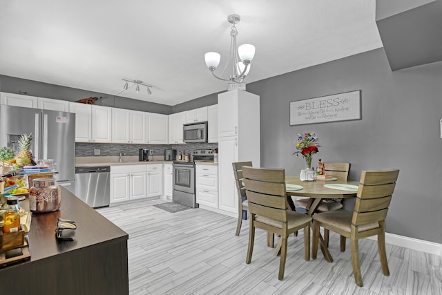 dining room featuring a chandelier, baseboards, and light wood-style floors