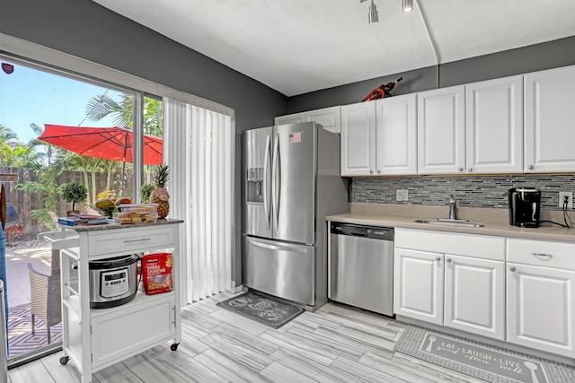 kitchen with appliances with stainless steel finishes, a sink, white cabinetry, and decorative backsplash