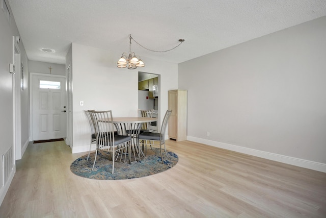 dining area featuring light wood-style floors, a chandelier, baseboards, and a textured ceiling