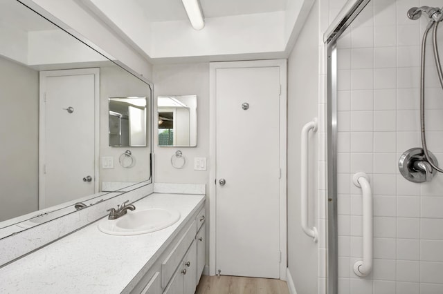 full bathroom featuring tiled shower, vanity, and wood finished floors