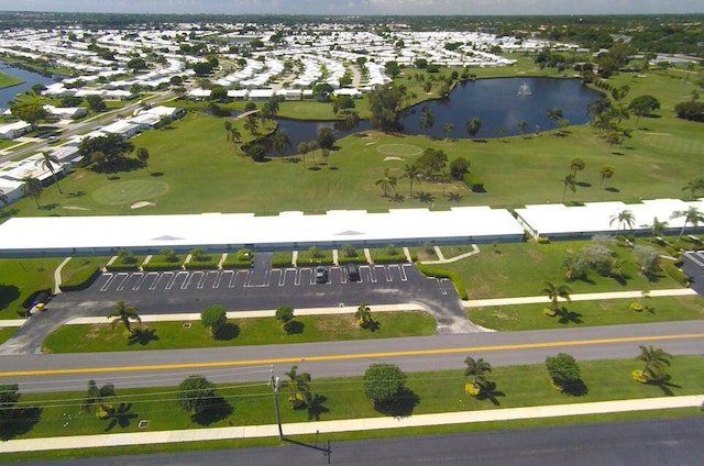 aerial view of property's location featuring a nearby body of water, a golf course, and nearby suburban area