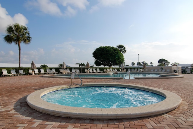 community pool with a hot tub and a patio