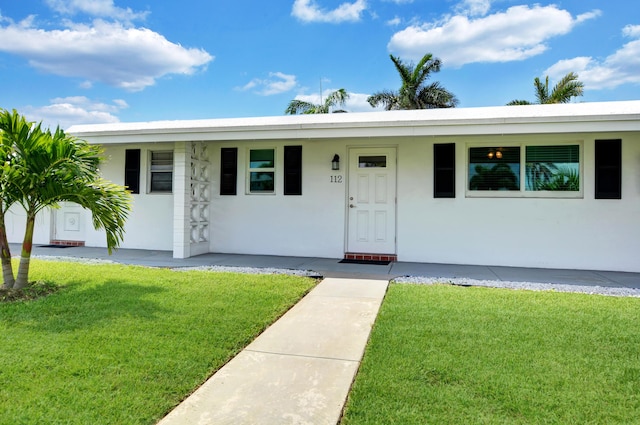 view of front facade with a front yard, stucco siding, and a porch