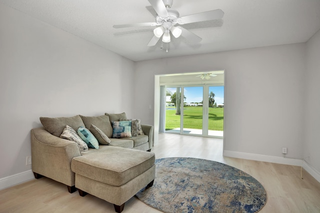 living area featuring light wood finished floors, baseboards, and a ceiling fan