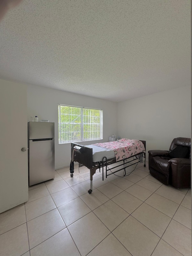 8305 NW 61st St Unit C309, Tamarac, FL 33321 - bedroom featuring freestanding refrigerator, a textured ceiling, and light tile patterned floors