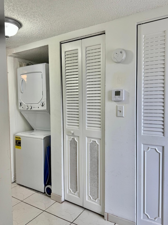8305 NW 61st St Unit C309, Tamarac, FL 33321 - washroom featuring stacked washer / drying machine, a textured ceiling, and baseboards