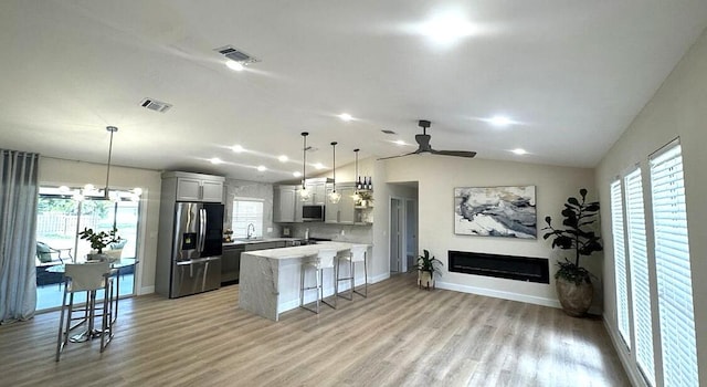 kitchen featuring appliances with stainless steel finishes, a sink, ceiling fan, plenty of natural light, and lofted ceiling