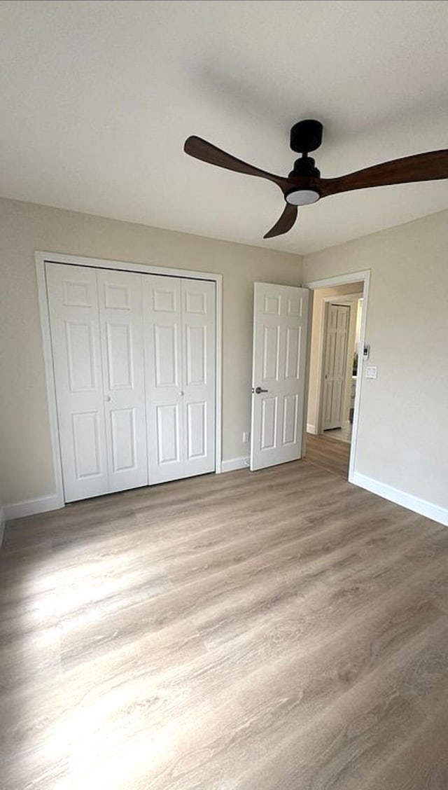 unfurnished bedroom featuring baseboards, a closet, wood finished floors, and ceiling fan