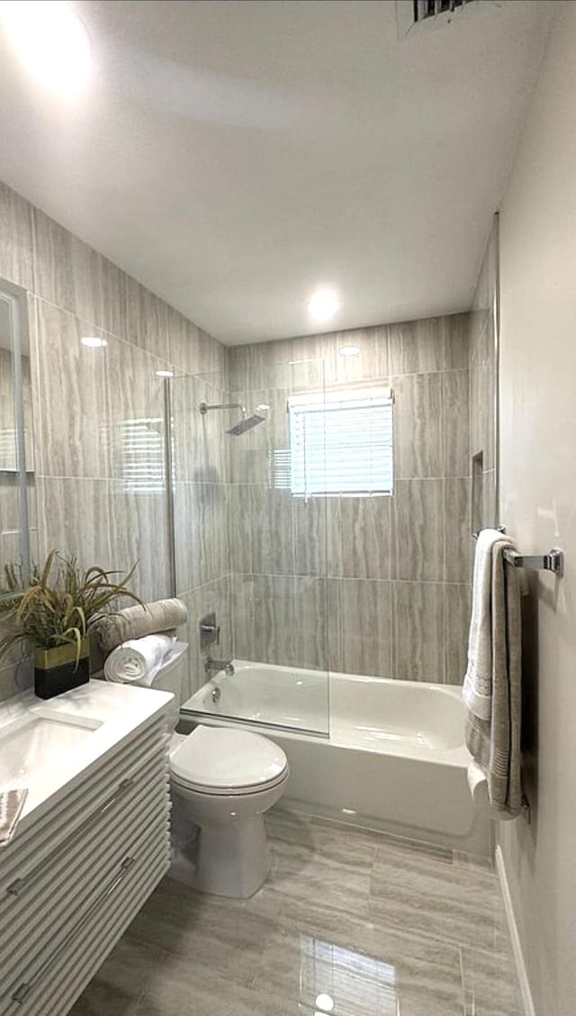 bathroom with washtub / shower combination, toilet, vanity, and baseboards