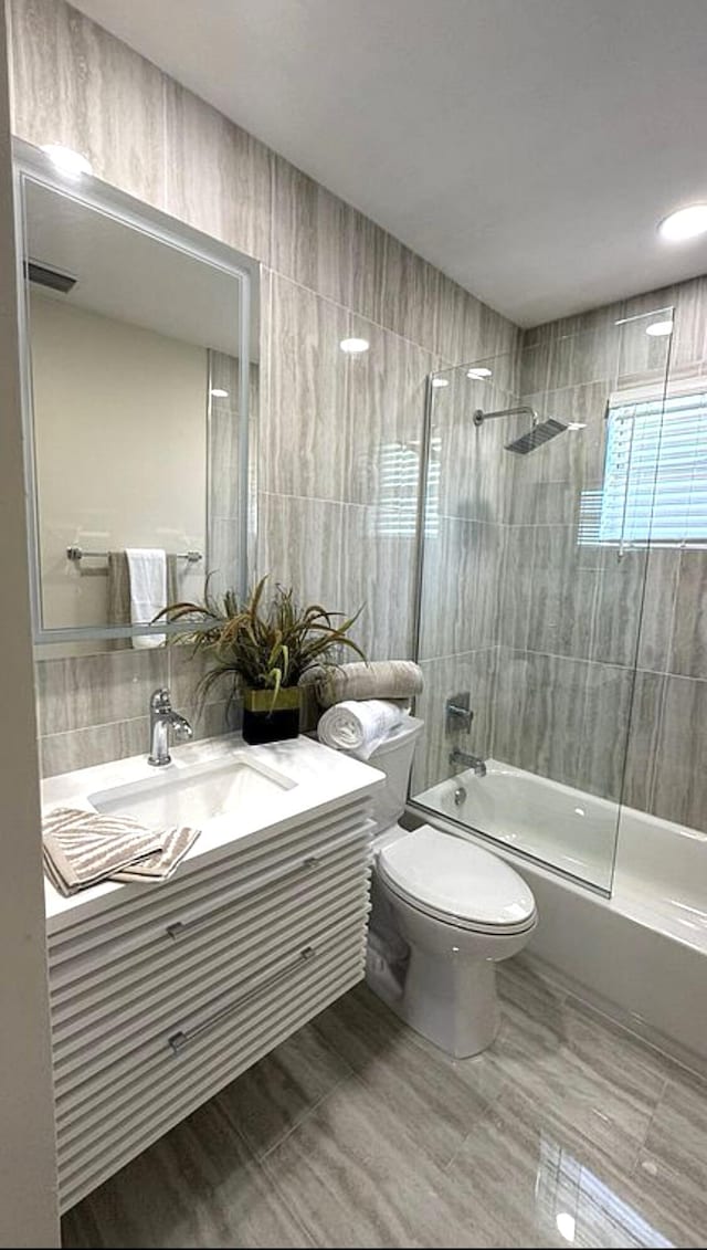 bathroom with tile walls, vanity, shower / washtub combination, toilet, and decorative backsplash