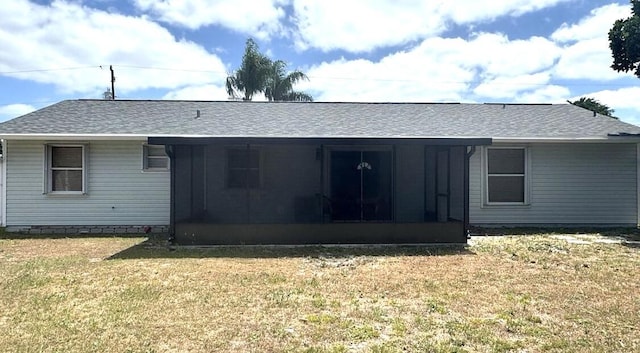 rear view of house with a yard, a sunroom, and roof with shingles