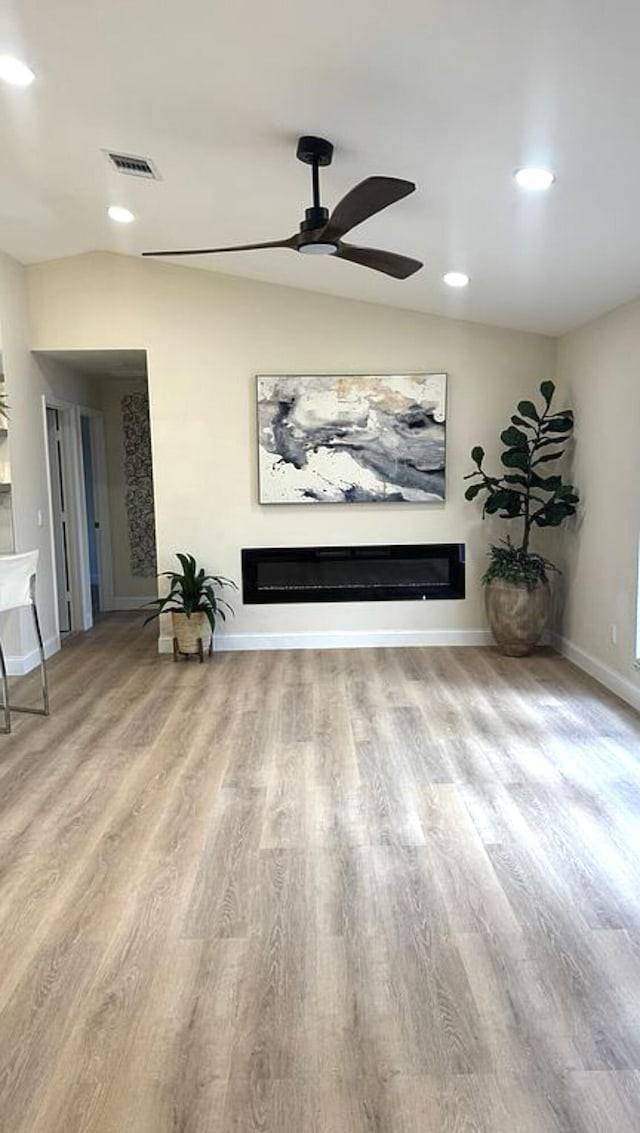 living area with a glass covered fireplace, wood finished floors, a ceiling fan, baseboards, and recessed lighting