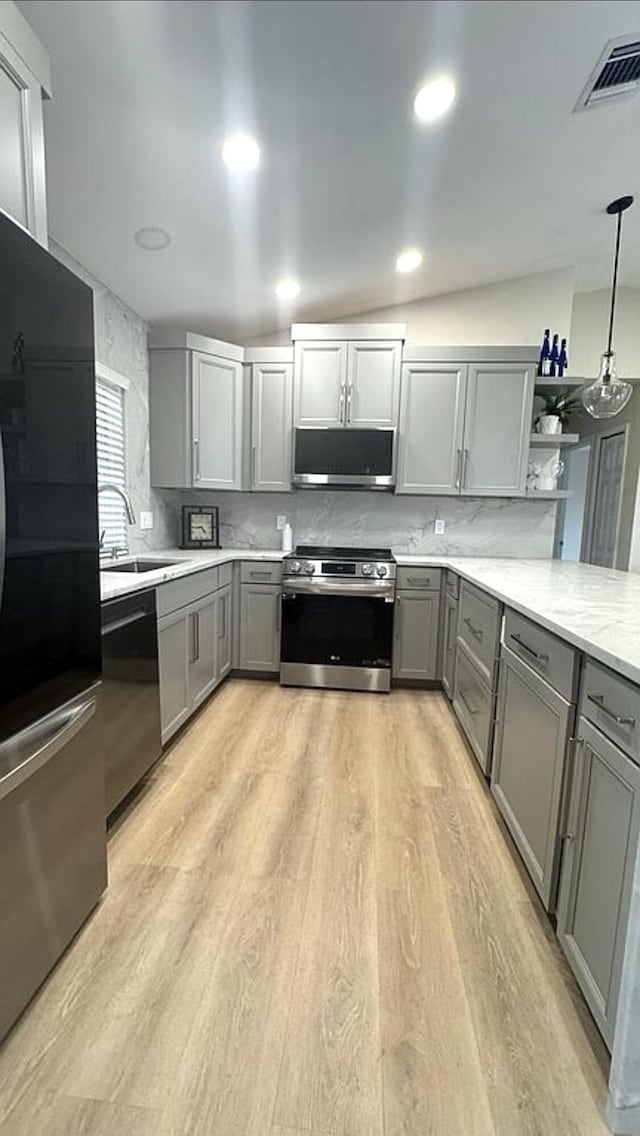 kitchen with appliances with stainless steel finishes, gray cabinets, a sink, and open shelves