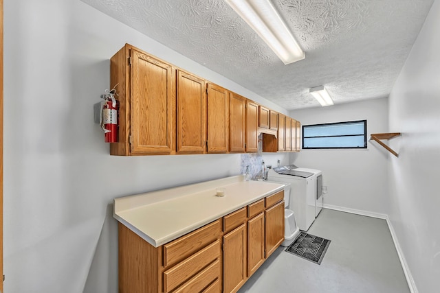 1290 SE Mcfarlane Ave, Port Saint Lucie, FL 34952 - laundry room with cabinet space, washing machine and clothes dryer, a textured ceiling, and baseboards