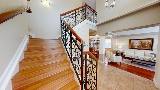 15511 63rd Pl N, Loxahatchee, FL 33470 - staircase with tile patterned floors, ornate columns, a chandelier, arched walkways, and baseboards