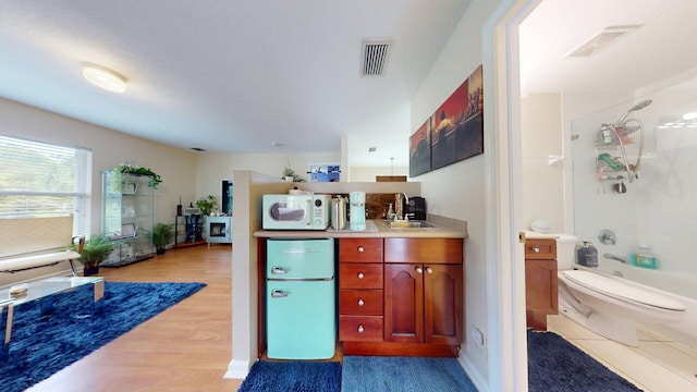 15511 63rd Pl N, Loxahatchee, FL 33470 - kitchen featuring fridge, a sink, white microwave, light wood finished floors, and light countertops
