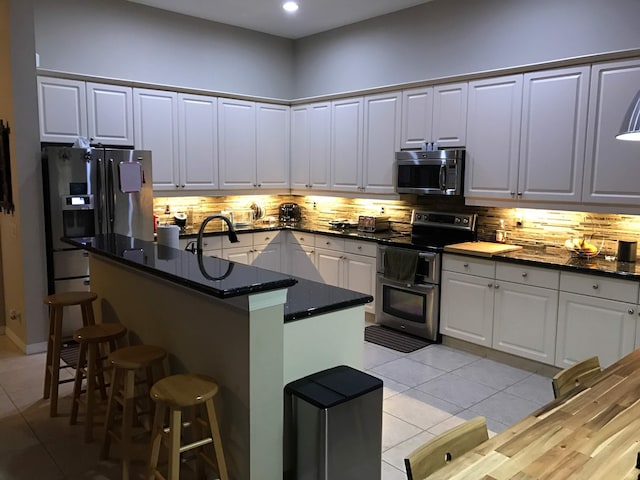 1366 Crossbill Ct, Weston, FL 33327 - kitchen featuring stainless steel appliances, light tile patterned flooring, a breakfast bar, tasteful backsplash, and recessed lighting