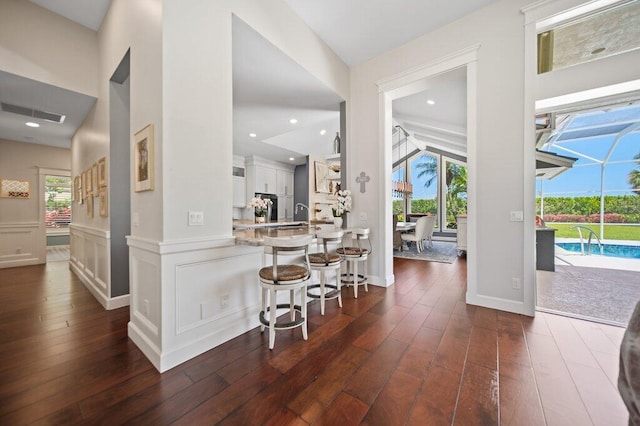 5211 SW Bimini Cir N, Palm City, FL 34990 - kitchen with dark wood-style flooring, light countertops, a breakfast bar area, white cabinets, and a sunroom
