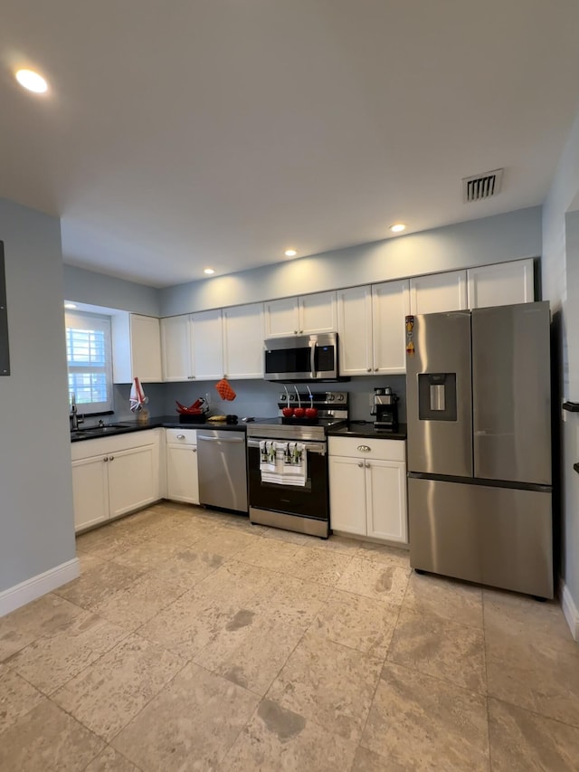 kitchen with appliances with stainless steel finishes, a sink, baseboards, dark countertops, and recessed lighting