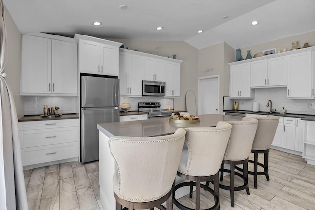 9794 Ridgecreek Rd, Boca Raton, FL 33496 - kitchen with stainless steel appliances, tasteful backsplash, vaulted ceiling, a center island, and white cabinets