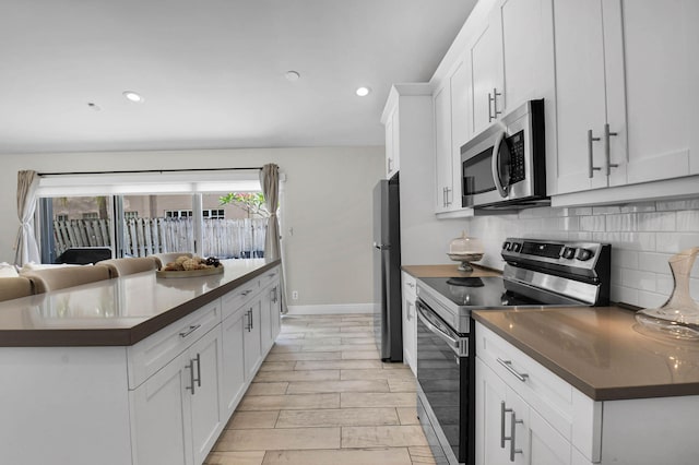 9794 Ridgecreek Rd, Boca Raton, FL 33496 - kitchen featuring appliances with stainless steel finishes, dark countertops, backsplash, white cabinets, and recessed lighting
